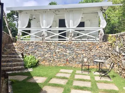 a house with a stone wall and a table and chairs at The Cottage at Javo beach in Las Galeras