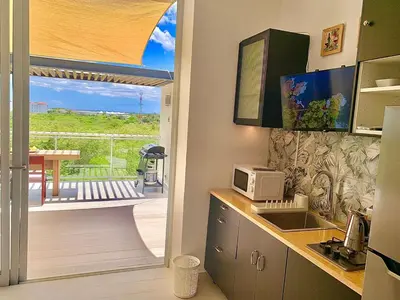 a kitchen with a microwave and a view of a deck at Vibe Residence Gorgeous Penthouse with Jacuzzi & outstanding Sea & Natural Preserve view in La Laguna