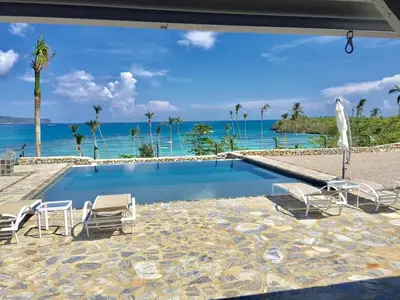 a swimming pool with chairs and the ocean in the background at The Bliss of JAVO BEACH in Las Galeras