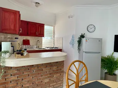 a kitchen with red cabinets and a white refrigerator at Villas Princesa Beach Apartments in Punta Cana