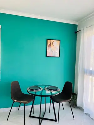 a table and chairs in a room with a green wall at Acogedor apartamento in Colorado