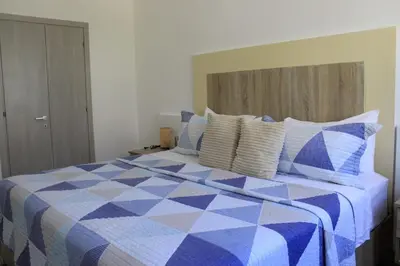 a bedroom with a blue and white bed with pillows at Depto entero, Coral Village D204, WIFI, TV, cerca de la playa in Punta Cana