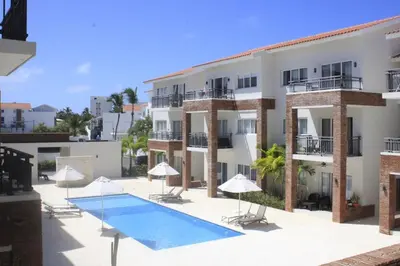 a large building with a swimming pool and umbrellas at Depto entero, Coral Village D204, WIFI, TV, cerca de la playa in Punta Cana