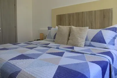 a blue and white quilt on a bed with pillows at Depto entero, Coral Village D204, WIFI, TV, cerca de la playa in Punta Cana