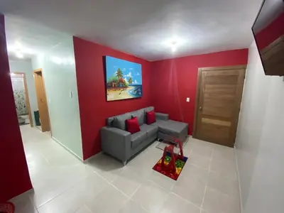 a living room with a couch and a red wall at 1st floor 3 Bedrm 2 Baths AC Condo near airport in Los Paredones
