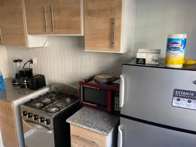 a small kitchen with a stove and a refrigerator at 1st floor 3 Bedrm 2 Baths AC Condo near airport in Los Paredones