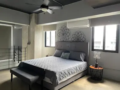 a bedroom with a bed and a fan and windows at PH Loft, 3floors,Private Jacuzzi n terrace,Kingbed in Santo Domingo