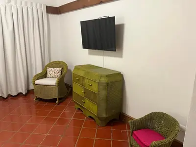 a room with two chairs and a dresser and a television at Casa de Campo Tenis Villa 16 in La Romana