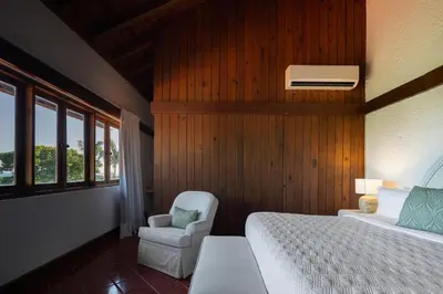 a bedroom with a bed and a chair at Casa de Campo Tenis Villa 16 in La Romana