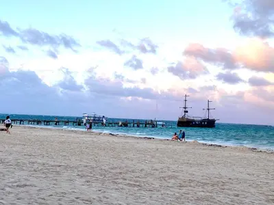 a group of people on a beach with a boat in the water at Amazing apartment pool and beach life in los corals punta cana in Punta Cana