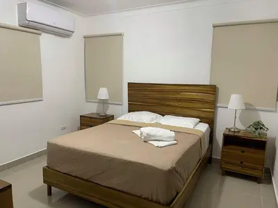 a bedroom with a large bed with two night stands and two lamps at Modern Apt in Santiago w Pool, 3 Bedrooms, Air conditioner in Santiago de los Caballeros
