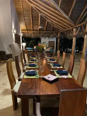 a wooden table with chairs and a long table with plates and glasses at Villa de Lima in Las Terrenas