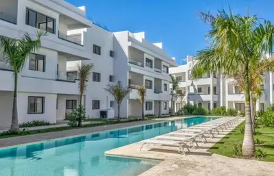 an apartment building with a swimming pool and palm trees at Penthouse con picuzzi privado y barbacoa en Bávaro in Punta Cana
