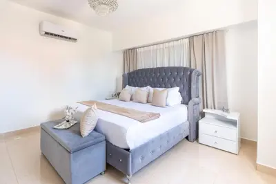 a bedroom with a blue bed with a blue chair at Modern Oasis near Monument with Rooftop BBQ , Gym, and Free Parking in Santiago de los Caballeros