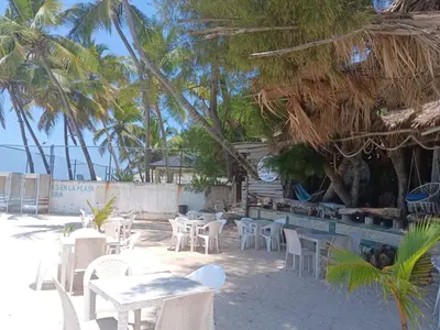 a restaurant with white tables and chairs on the beach at 1Vida Bar Restaurante in Guayacanes