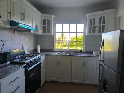a kitchen with white cabinets and a stove and a window at Cana Esmeralda in Punta Cana