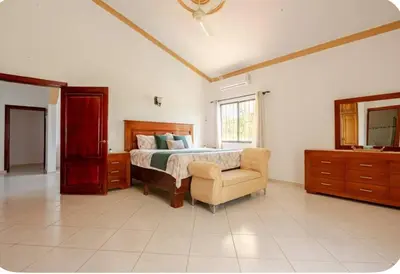 a bedroom with a bed and a chair and a mirror at Rio San Juan,Spacious,Local,3 Bedroom in Río San Juan