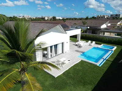 a white house with a swimming pool and a palm tree at VILLA CORAL Tracadero Beach Resort in La Laguna