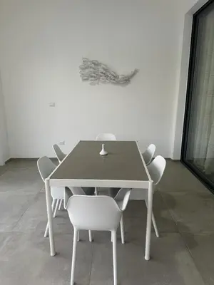 a table with white chairs and a white wall at VILLA CORAL Tracadero Beach Resort in La Laguna