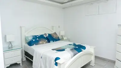 a white bedroom with a white bed with blue pillows at Villa Rosa Boca Chica in Boca Chica
