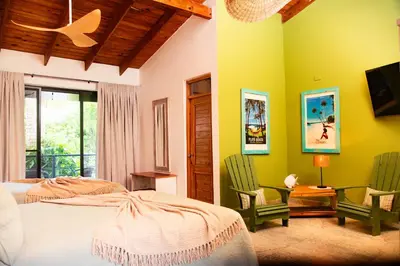 a bedroom with a bed and two green chairs at Central Hotel Boutique in Las Galeras