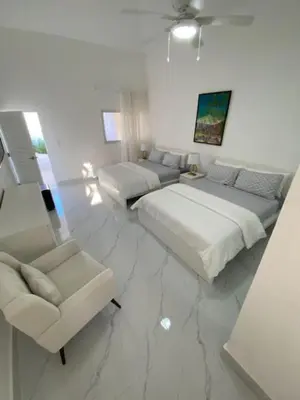 a white room with two beds and a chair at Villa Allegria Los Lagos 57 in La Romana