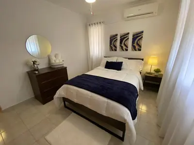 a bedroom with a large bed with a blue blanket at FreshBreeze - Apartment Near US Embassy in Santo Domingo