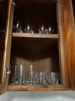 a row of glasses in a wooden cabinet at Villa Gordon in Santa Cruz de Barahona