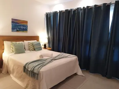 a bedroom with a bed with blue curtains at Comfort one step away from the beach in Las Terrenas