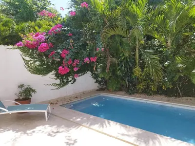 a swimming pool in a garden with pink flowers at Comfort one step away from the beach in Las Terrenas