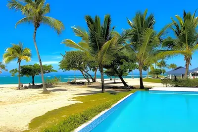 a resort swimming pool with palm trees and the beach at Paraíso Soleado, apartamento en la playa in Sampiño