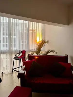 a living room with a red couch in front of a window at 3BR & Rooftop Jacuzzi Near Beach in Las Terrenas