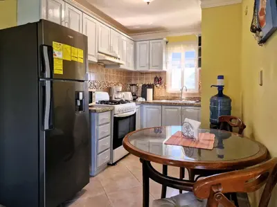 a kitchen with a table and a refrigerator at Garden Condo, Sosua in Sosúa