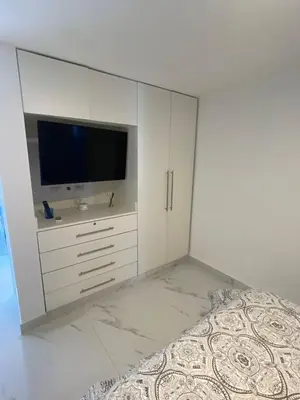 a white bedroom with a tv and a bed at Luxury apartment Playa Dorada in Puerto Plata