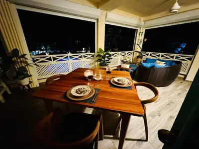a wooden table with plates and wine glasses on a balcony at Las Terrenas La Dolce Vita 7, Captivating and Exciting in Las Terrenas