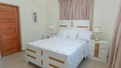 a bedroom with a large white bed and two lamps at Agua Azul Boca Chica Accommodation in Andrés