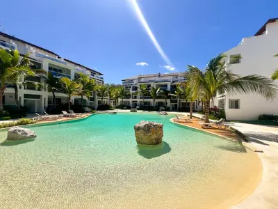 a swimming pool with a rock in the water in front of buildings at Dimary Charming Apt, 5 Pools, Walk to the Beach Dominicus Bayahibe la Romana in La Laguna