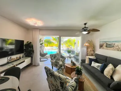 a living room with a couch and chairs and a tv at Dimary Charming Apt, 5 Pools, Walk to the Beach Dominicus Bayahibe la Romana in La Laguna
