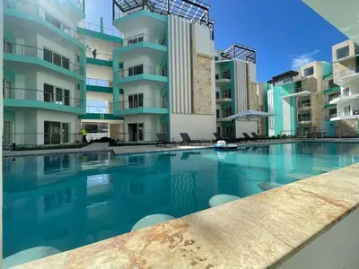 a swimming pool in front of a building at Maple Beach, apartamento en Punta Cana in Punta Cana