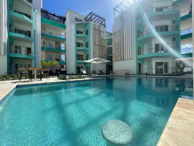 a swimming pool in front of a building at Maple Beach, apartamento en Punta Cana in Punta Cana