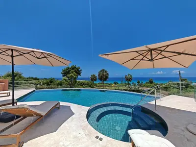 a swimming pool with two umbrellas and a swimming poolvisor at Luxury Oceanfront Villa with Heated Pool, Jacuzzi, AC, BBQ, Starlink Wi-Fi, Chef's Kitchen, Staff Included, Mountain Views, Near El Quemaito, San Rafael, and Los Patos Beach in Santa Cruz de Barahona