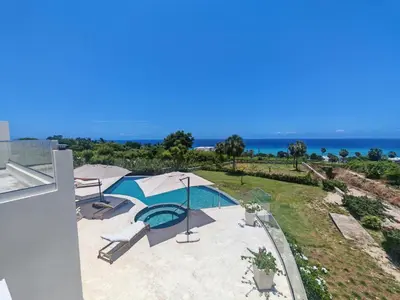 an outdoor swimming pool with umbrellas and the ocean at Luxury Oceanfront Villa with Heated Pool, Jacuzzi, AC, BBQ, Starlink Wi-Fi, Chef's Kitchen, Staff Included, Mountain Views, Near El Quemaito, San Rafael, and Los Patos Beach in Santa Cruz de Barahona