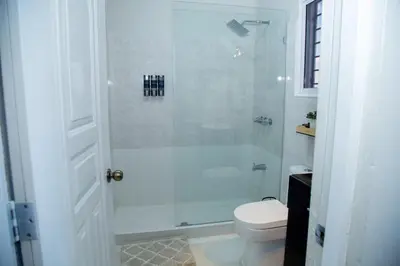 a white bathroom with a shower and a toilet at Luxury Apartment in Santiago de los Caballeros