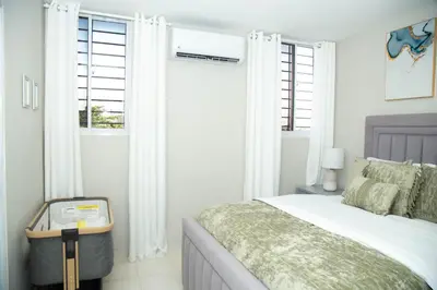 a white bedroom with a bed and two windows at Luxury Apartment in Santiago de los Caballeros