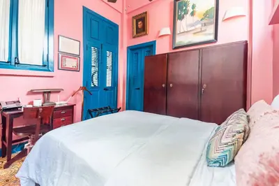 a bedroom with a bed with a blue door and a desk at Stylish Colonial Townhouse in Santo Domingo's Historic Heart in Santo Domingo