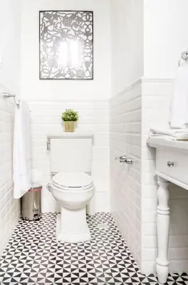 a bathroom with a toilet and a black and white tile floor at Stylish Colonial Townhouse in Santo Domingo's Historic Heart in Santo Domingo