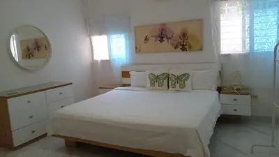 a white bedroom with a large bed and a mirror at Cozy apartment in Boca Chica in Boca Chica