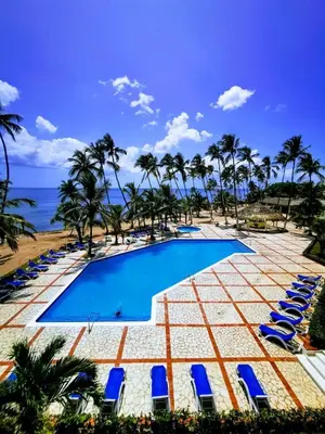 a pool with chairs and palm trees and the ocean at Juan Dolio paradise in Villas del Mar