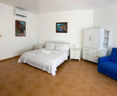 a bedroom with a white bed and a blue chair at Appartamento Albatros, Juan Dolio in Juan Dolio