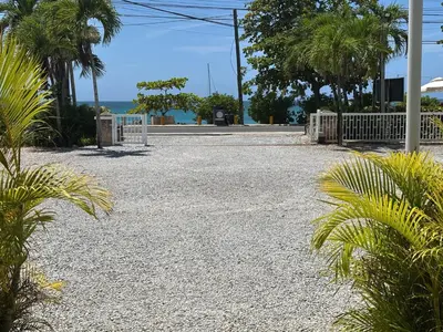 a gravel parking lot with palm trees and the ocean at Apartment en residence face à la Mer in Las Terrenas